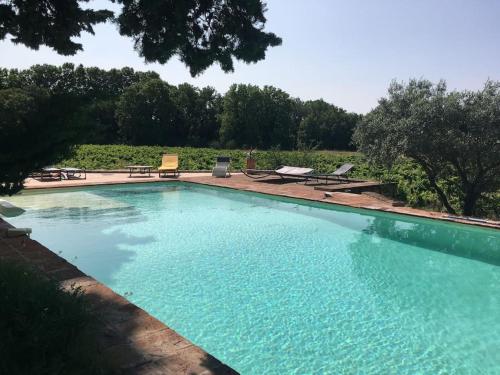 une grande piscine avec de l'eau bleue dans une cour dans l'établissement Gite des amis Domaine de Mas Caron, à Caromb