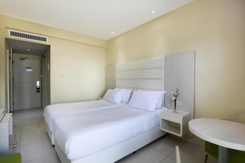 a bedroom with a large white bed and a table at Tasia Maris Beach Hotel - Adults Only in Ayia Napa