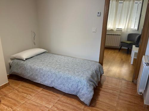 a bedroom with a bed and a chair in a room at Apartamento junto al parque in Ponferrada