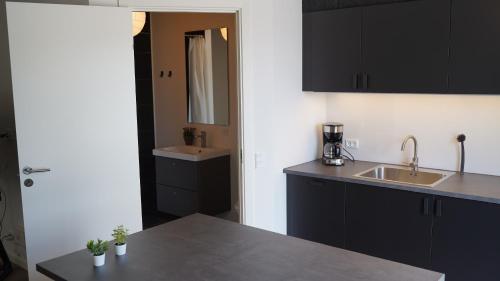 a kitchen with black cabinets and a sink at Holiday Apartments Tønder in Tønder