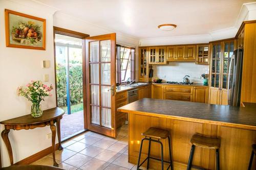 a kitchen with wooden cabinets and a counter with a table at Quaint, Charming Pumicestone Cottage - Beach Charm - ZA7 in Golden Beach