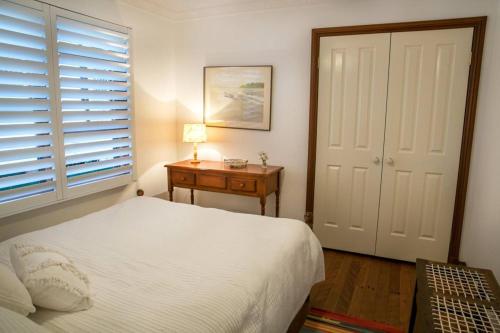 Luxury Pumicestone Cottage - Beach Charm - ZA7 في Golden Beach: غرفة نوم بسرير وطاولة ونافذة