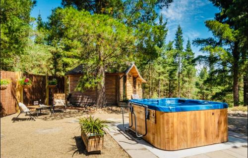 uma banheira de hidromassagem num quintal com uma casa em Fairytale Log Cabin - Homewood Forest Retreat em Alexandra