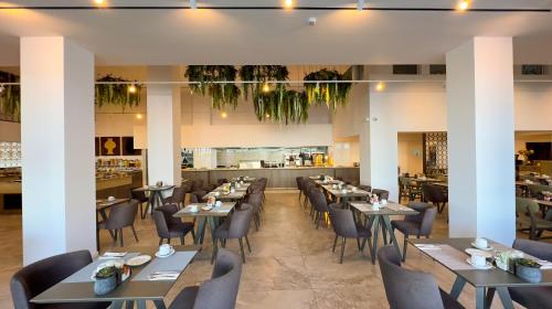 a restaurant with tables and chairs and a bar at Tasia Maris Beach Hotel - Adults Only in Ayia Napa