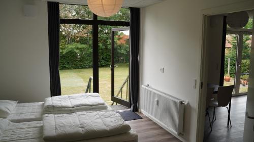 1 dormitorio con cama, escritorio y ventanas grandes en Holiday Apartments Tønder, en Tønder