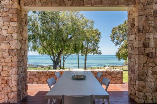 Un patio con paredes de piedra con mesa y sillas. en Bay Watch I Private Properties, en Dunsborough