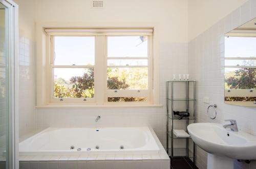 ein weißes Badezimmer mit einer Badewanne und einem Waschbecken in der Unterkunft Longview Vineyard in Macclesfield