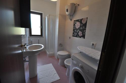 a white bathroom with a sink and a toilet at Zefiro Casa Vacanze in Ascea