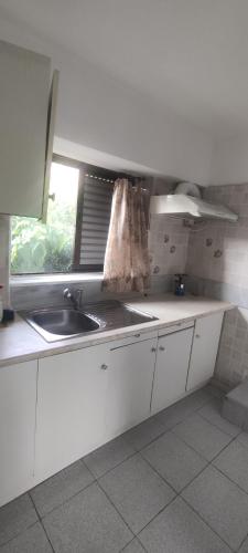 d'une cuisine avec des placards blancs, un évier et une fenêtre. dans l'établissement Efterpi Aggeli, à Loutrópolis Thermís