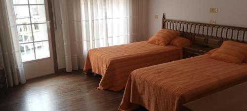 Habitación de hotel con 2 camas y ventana en PENSION RESTAURANTE CASANOVA, en Puebla de Trives