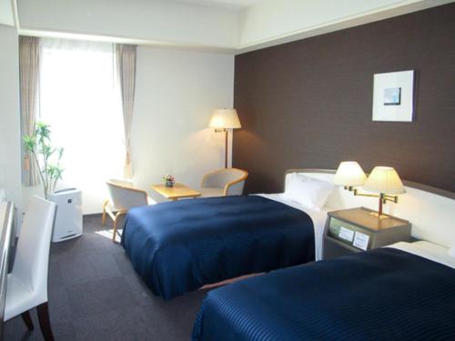 una camera d'albergo con 2 letti e una scrivania di HOTEL LiVEMAX BUDGET SAPPORO a Sapporo
