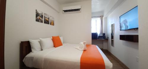um quarto com uma cama com almofadas laranja e branca em Voyager Sun & Reef Hotel em San Pedro