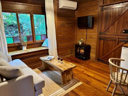 a living room with a couch and a table and a stove at Koompartoo Retreat Bellingen in Bellingen
