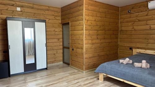 a bedroom with wooden walls and a bed and a mirror at ЛИЛИЯ in Gudauta