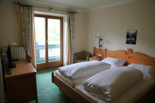 una camera da letto con due letti, una scrivania e una finestra di Hotel Voglauerhof ad Abtenau
