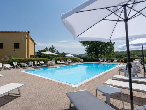 una piscina con sillas y sombrilla en Surrounded by the beautiful sloping Tuscan landscape, en Casole dʼElsa