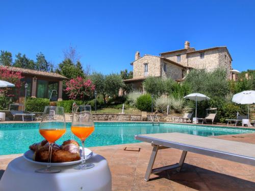 アッシジにあるPicturesque Holiday Home in Assisi with Poolのプールサイドのテーブルの上でのワイン2杯