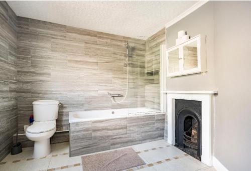 a bathroom with a tub and a toilet and a fireplace at Maidstone castle 3bedroom free sports channels, parking in Kent