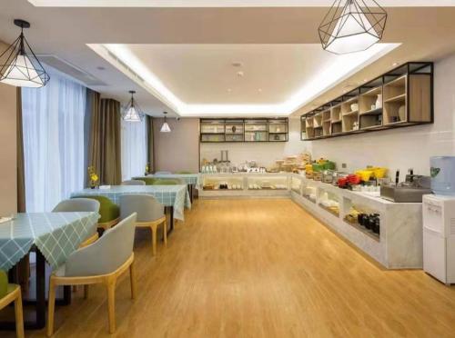 a restaurant with tables and chairs and a kitchen at Morninginn, Meixi Lake West Bus Station in Changsha