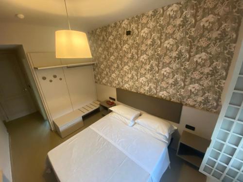 a small bedroom with a white bed and a floral wallpaper at Artua'&Solferino in Turin