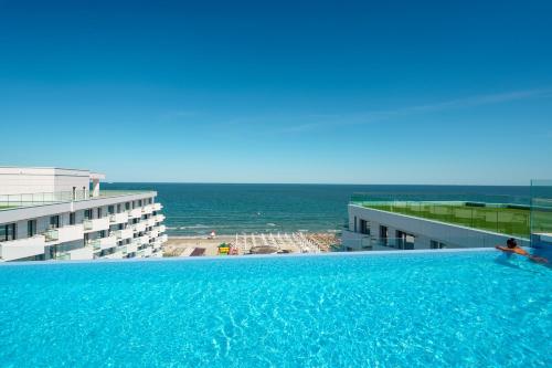 a large swimming pool with a view of the ocean at Royale Sundance 305 Infinity Beach Pool & Spa Mamaia Nord in Mamaia Nord