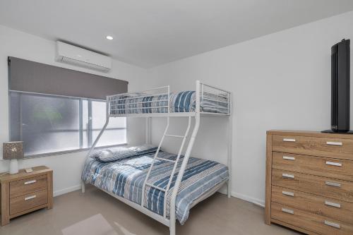 a bedroom with a bunk bed and a dresser at Endeavour Holiday House Clifton Beach in Clifton Beach