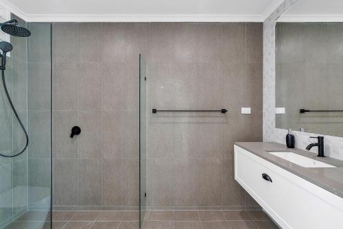 a bathroom with a glass shower and a sink at Endeavour Holiday House Clifton Beach in Clifton Beach