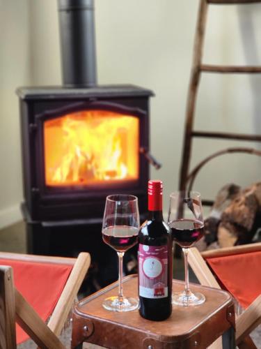 two glasses of red wine on a table with a fireplace at Red Door Collective - RDC Vineyard Estate in Pokolbin