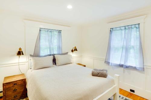 a white bedroom with a bed and two windows at Secluded Elka Park Cabin Hot Tub and Fire Pit! in Elka Park