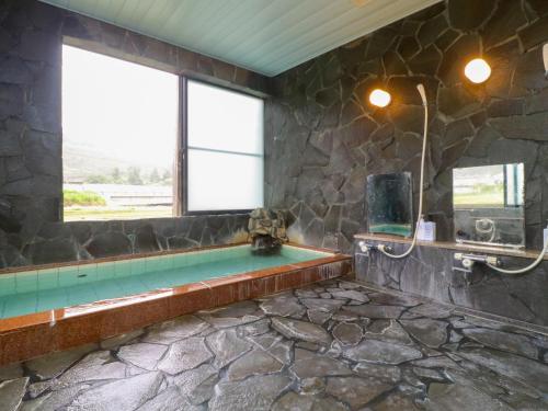 a stone bathroom with a tub and a window at サンバレーひぐち in Muikamachi