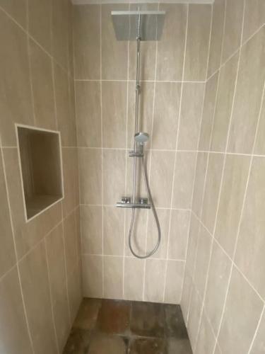La salle de bains carrelée est pourvue d'une douche avec un tuyau. dans l'établissement Maison neuve avec piscine chauffée, 4 kms de Contis plage, à Saint-Julien-en-Born