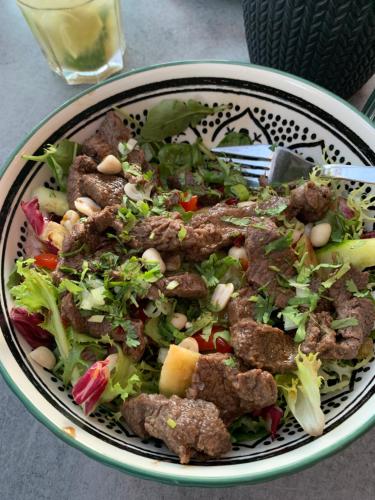 a bowl of food with meat and salad on a table at MobileHome 8 Personnes avec Clim situé aux Sables du Midi in Valras-Plage