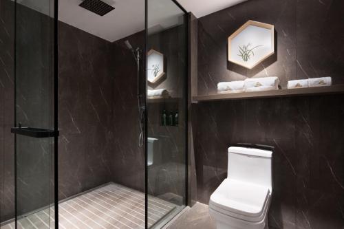 uma casa de banho com um WC e uma cabina de duche em vidro. em Morning Hotel, Changsha Guihuaping Metro Station em Changsha