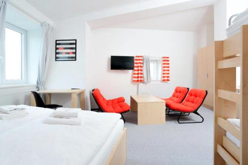 a bedroom with red chairs and a bed and a desk at Penzion Kraličák in Staré Město