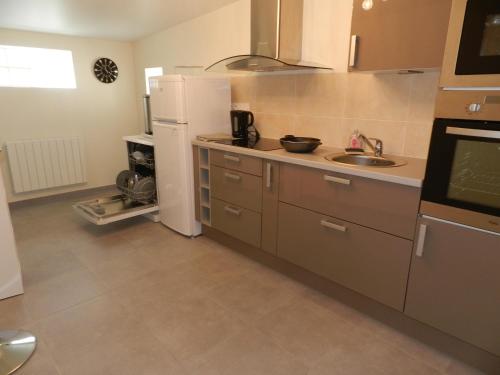 a kitchen with a sink and a white refrigerator at Gîte Utah in Saint-Laurent-sur-Mer