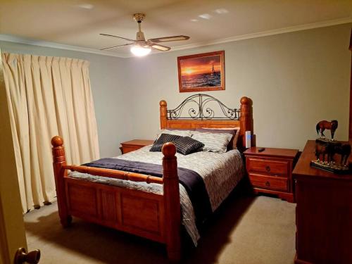 a bedroom with a wooden bed and a dresser and a ceiling fan at Welcome to Schnippen Inn. in Tanunda