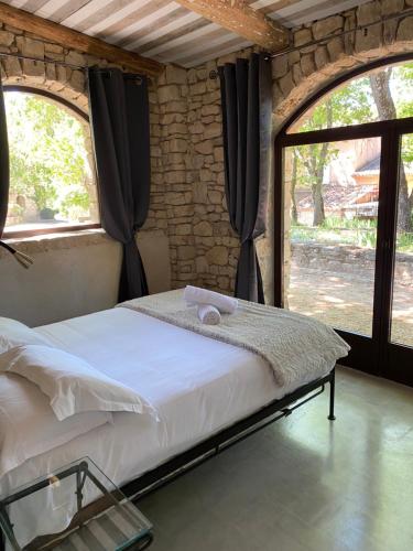 a bed in a room with a stone wall at Hôtel Lou Caleù restaurant le Rocher des Abeilles in Saint-Martin-de-Castillon