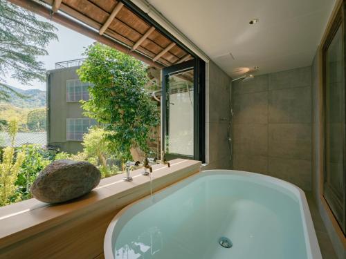 uma banheira na casa de banho com uma grande janela em 巛-sen-湯河原 em Yugawara