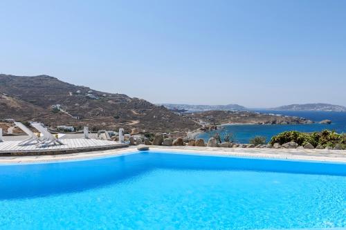 a large blue swimming pool with a view of the ocean at Seablue Villas in Houlakia