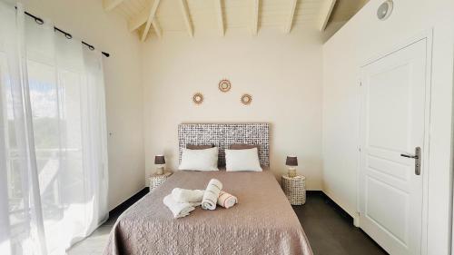 a bedroom with a bed with two shoes on it at Le Martini-Vue MER et PINEL terrasse piscine in Cul de Sac