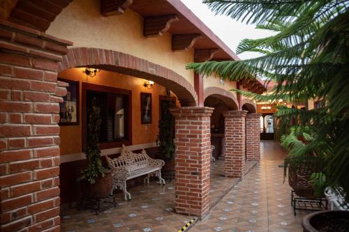 un patio al aire libre con un banco y un edificio de ladrillo en Hotel El Patio, en Tequisquiapan