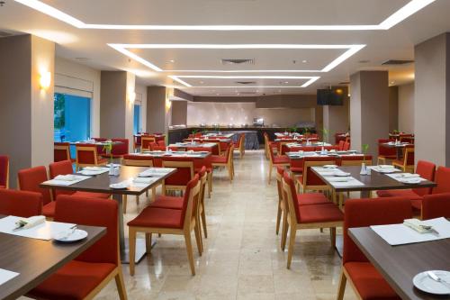 un restaurante con mesas de madera y sillas rojas en Courtyard by Marriott Villahermosa Tabasco en Villahermosa