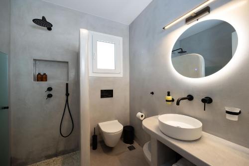 a bathroom with a sink and a toilet and a mirror at OLIVES seaside villas villa no 2 in Plaka