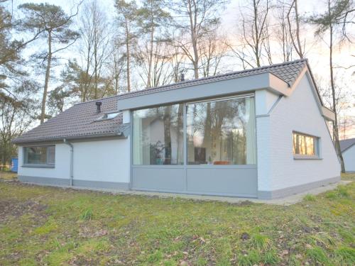 a small white house with a large window at Alluring Holiday Home in Limburg near Forest in De Horst
