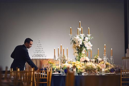 a man walking past a table with flowers and candles at The Ritz-Carlton, Kuala Lumpur in Kuala Lumpur