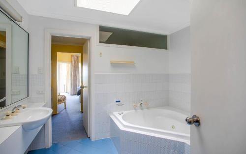 uma casa de banho branca com uma banheira e um lavatório em Beachfront Great for the Family em Encounter Bay