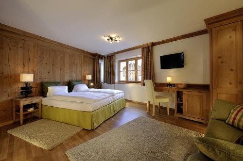 a bedroom with a bed and a desk and a tv at Hotel Garni Albona in Sankt Anton am Arlberg