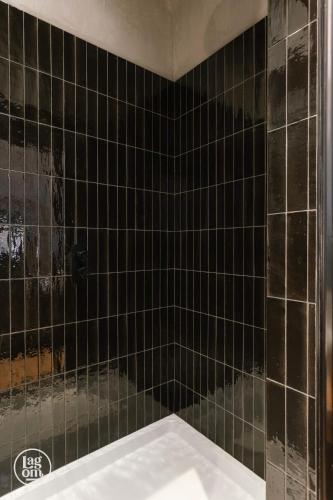a bathroom with black tiled walls and a tub at StayLagom in Ballycastle