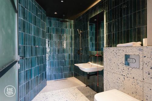 ein blau gefliestes Bad mit einem Waschbecken und einem WC in der Unterkunft StayLagom in Ballycastle