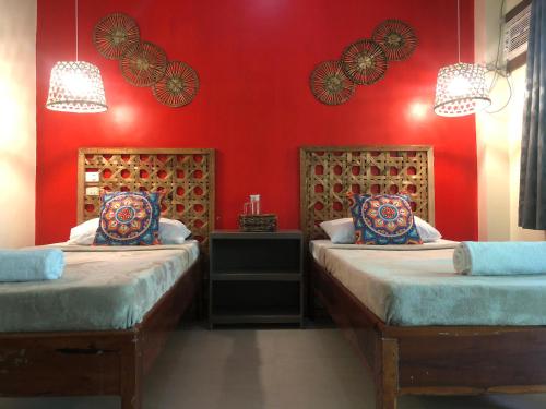 two beds in a room with red walls at Coracasa bed and breakfast in General Luna